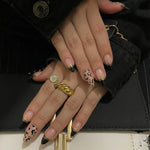 Load image into Gallery viewer, Close-up of a hand with manicured nails and rings, holding a black handbag.