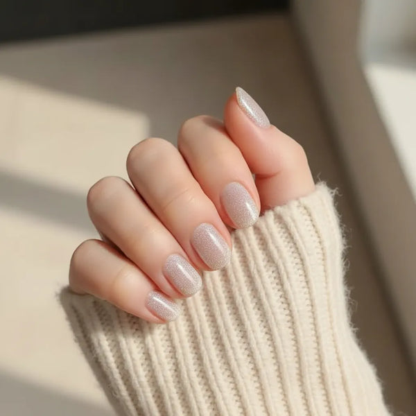 Hand with sparkly nail polish on a neutral background