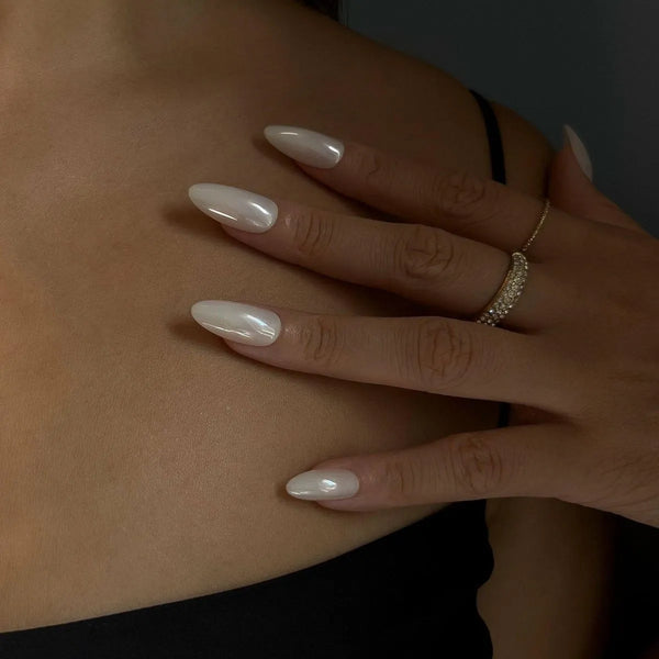 Close-up of a hand with long, white nail polish on a dark background
