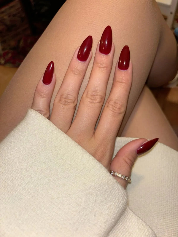 Close-up of a hand with red nail polish wearing a white sleeve.