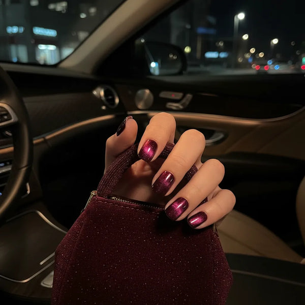 Hand with maroon nail polish holding a small bag inside a car at night.