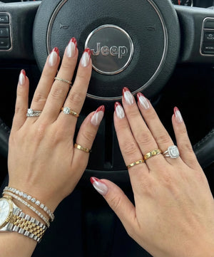 Hands with manicured nails and rings in front of a Jeep steering wheel