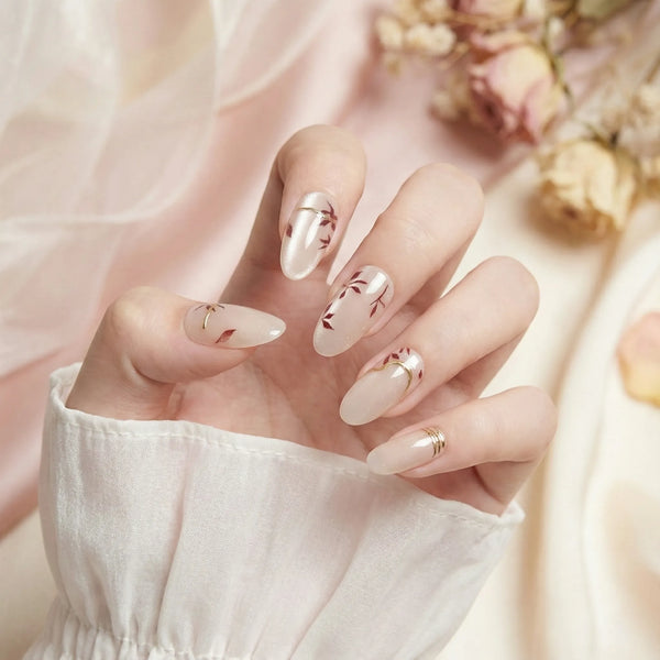 Hand with beige nail polish and gold accents against a soft pink background