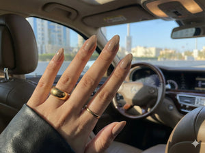 Hand with manicured nails and gold rings in a car interior