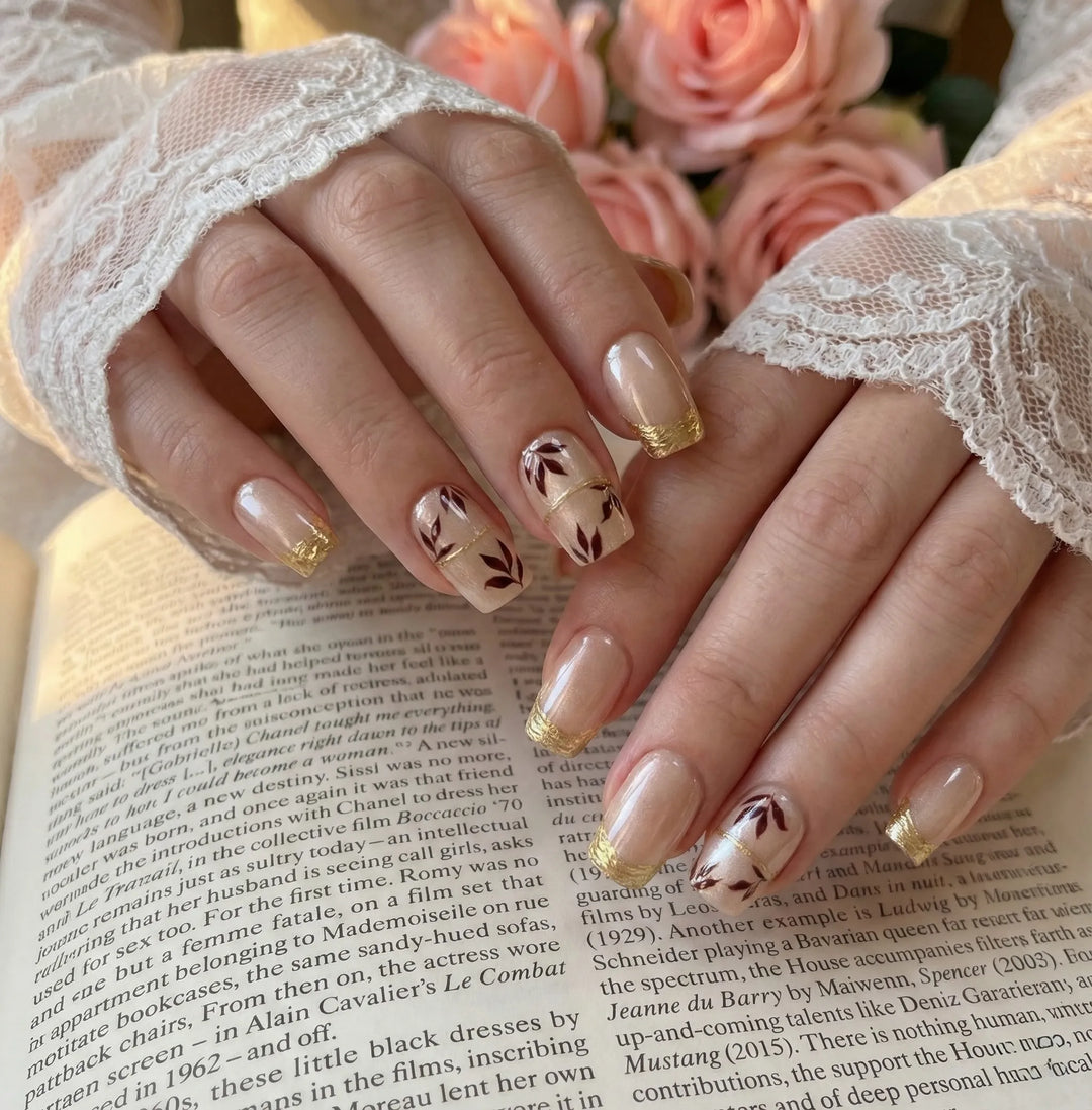 Close-up of hands with decorative nail art on a book page with pink flowers in the background