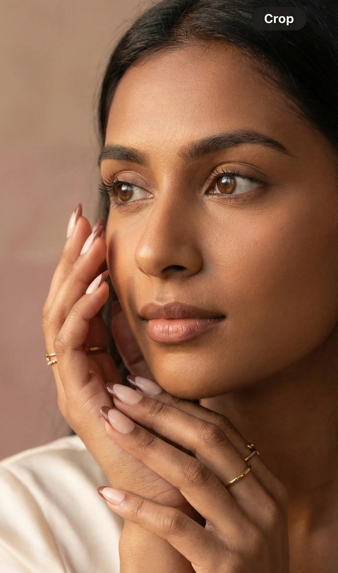 Woman applying makeup with a brush on a neutral background